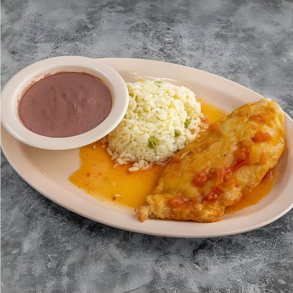 A chile relleno with rice and refried beans on a light pink oval plate.