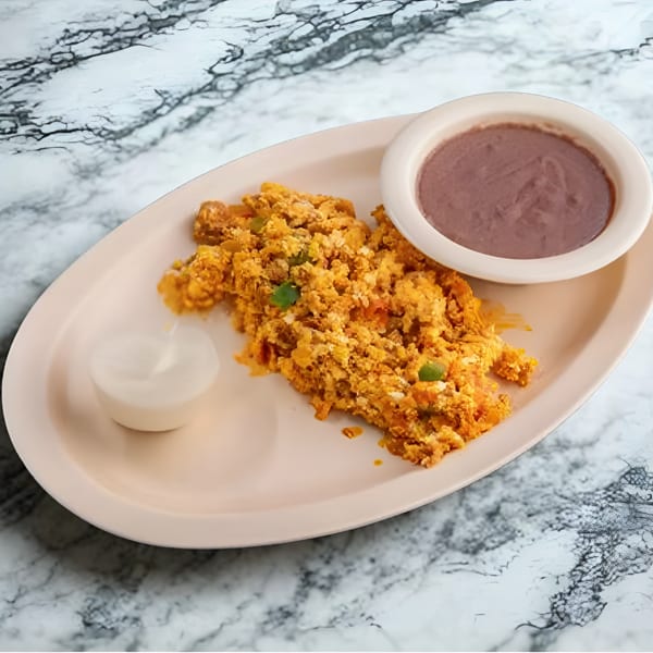 Scrambled eggs with green peppers, a side of refried beans, and sour cream on a marble table.